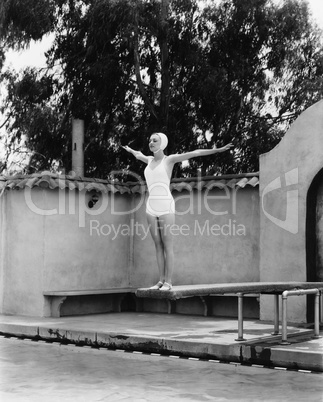 Woman on diving board at swimming pool