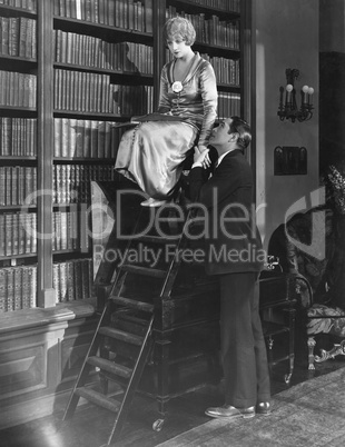Man with woman on ladder in library