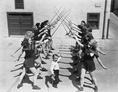 Teenage girls and little boy fencing