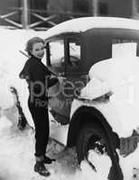 Woman shoveling snow off car