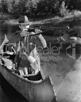 Man aiming gun from canoe