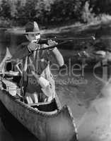 Man aiming gun from canoe