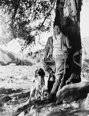 Portrait of hunter and dog under tree