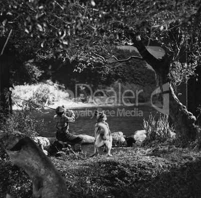 Boy fishing with dog in river