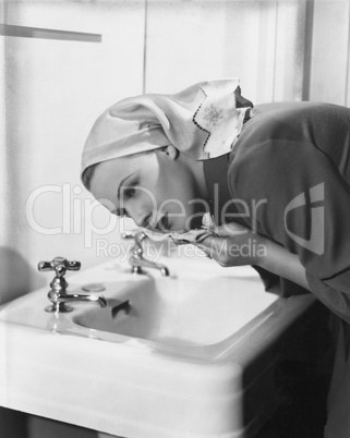 Woman washing face over sink