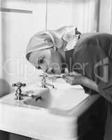Woman washing face over sink