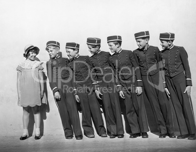Line of young bellhops smiling at girl