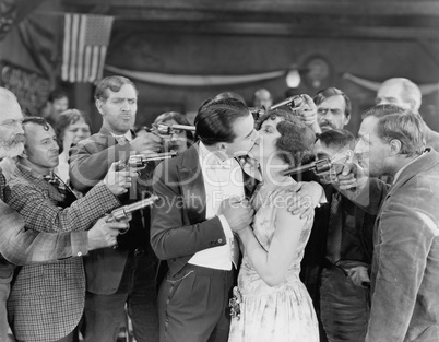 Kissing couple surrounded by men with guns