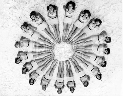 Women lying in circle around beach ball