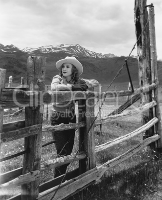 Woman leaning on wooden fence on ranch