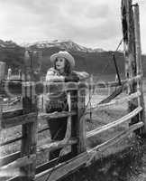 Woman leaning on wooden fence on ranch