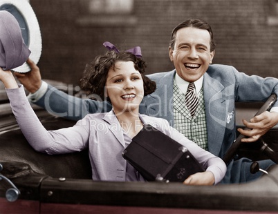 Portrait of happy couple waving in car