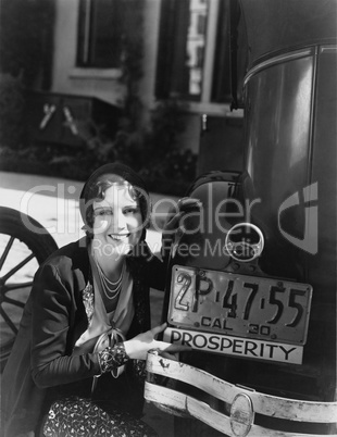 Woman with prosperity sign on car bumper