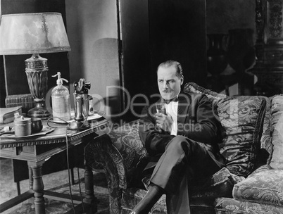 Thoughtful man having a drink on couch