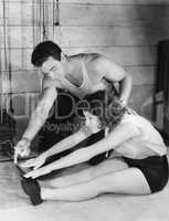 Woman stretching with help from trainer