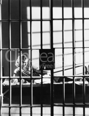 Woman through bars of jail cell