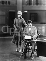 Woman interrupting man at typewriter