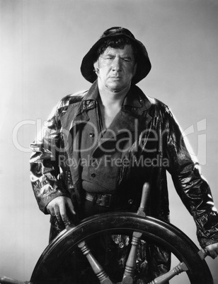 Man in raincoat steering boat