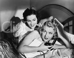 Two women in bed with telephone