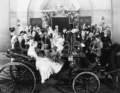 Newlyweds leaving wedding in carriage