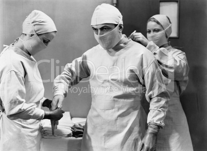 Women preparing doctor for surgery