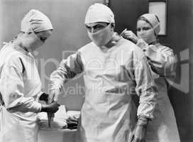 Women preparing doctor for surgery