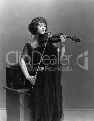 Woman playing violin with headphones