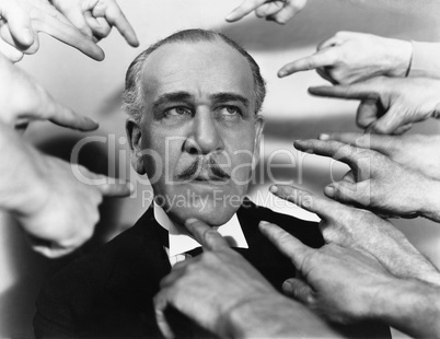 Closeup of many fingers pointing at man