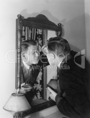 Man at mirror combing hair