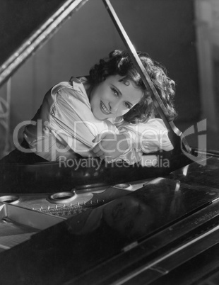 Portrait of woman leaning on piano