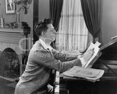 Man at piano writing on sheet music