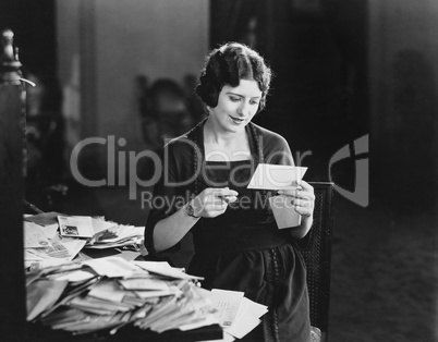 Woman reading letter with pile of mail