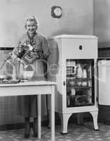 Woman with refrigerator and mixer in kitchen