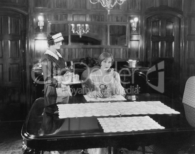 Maid serving woman at table