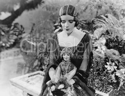 Woman sitting in garden with doll