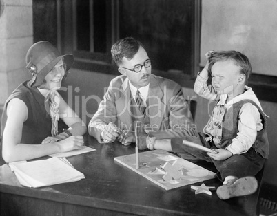 Adults testing little boy doing puzzle