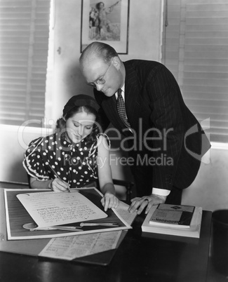 Man overseeing woman signing document