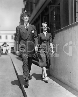 Smiling couple walking on sidewalk