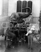 Man holding child and washing elephant
