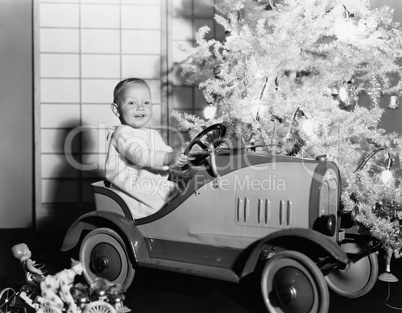 Child with toy car under Christmas tree