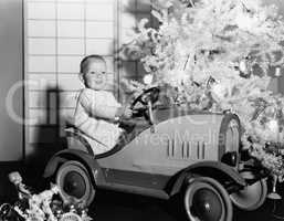 Child with toy car under Christmas tree