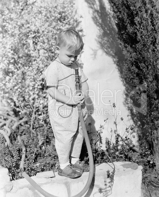Child pointing hose at face