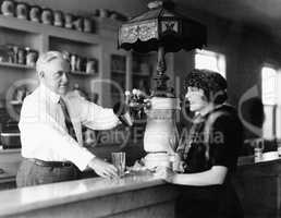 Man serving beverage to woman at counter