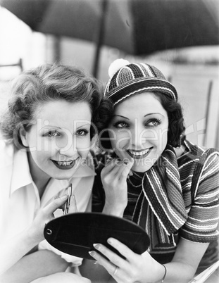 Two women putting on makeup