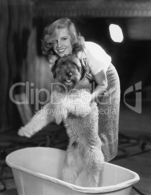 Woman bathing dog in tub