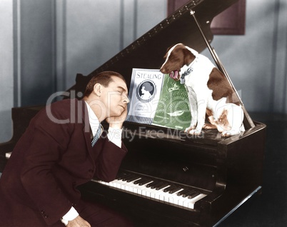 Man asleep at piano with dog