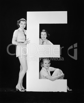 Women posing with huge letter E