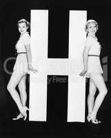 Women posing with huge letter H