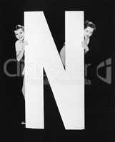 Two women hiding behind huge letter N