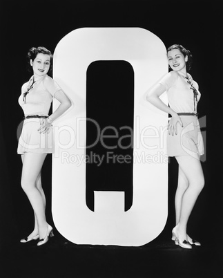Women posing with huge letter Q